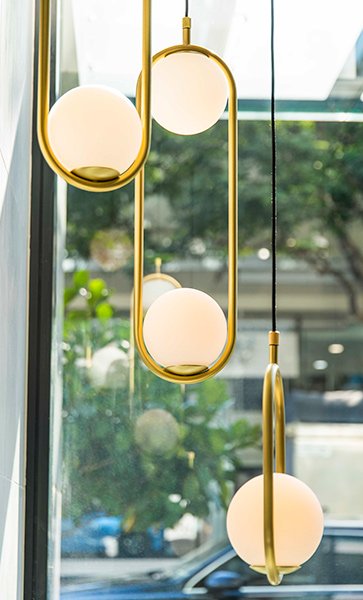 Hanging spherical lamps pictured in front of a window looking onto a street