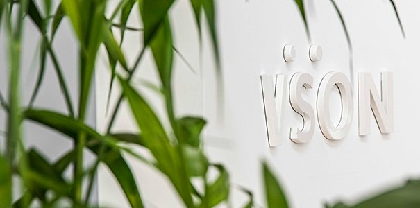 White VSON laser eye surgery clinic sign on white wall with plants in foreground