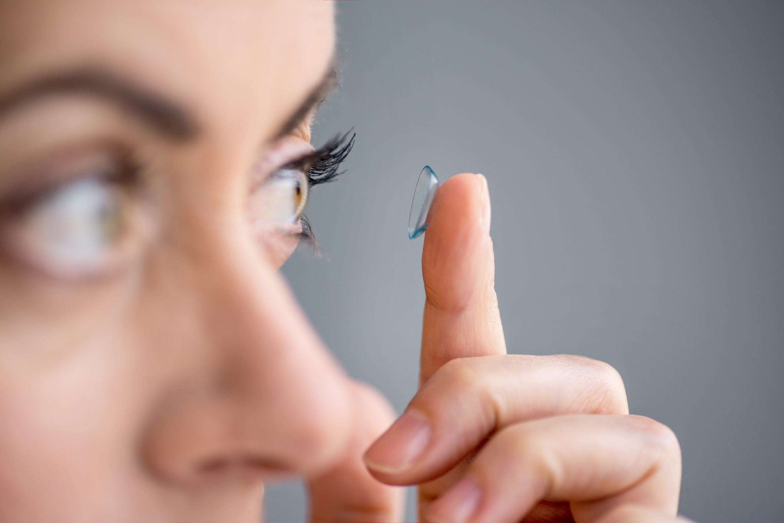 Woman putting in contact lenses while contemplating the best time to have laser eye surgery