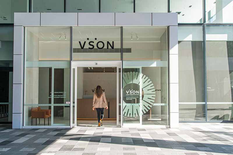 Woman in blaser jacket viewed from behind entering the VSON laser eye surgery clinic in Brisbane