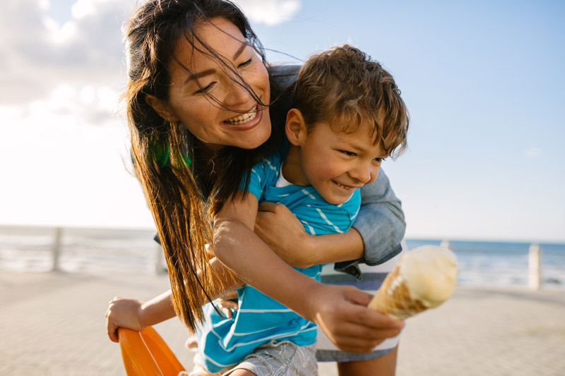 A middle-aged mom enjoying a holiday at the beach with her son after undergoing laser eye surgery