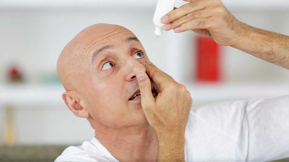 Middle-aged man putting in eye drops to treat symptoms of presbyopia