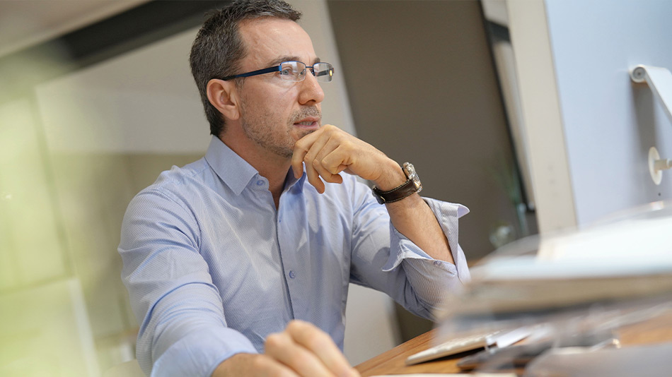 Middle-aged man with reading glasses reading an article about the possibility of experiencing dry eyes after lens replacement surgery.