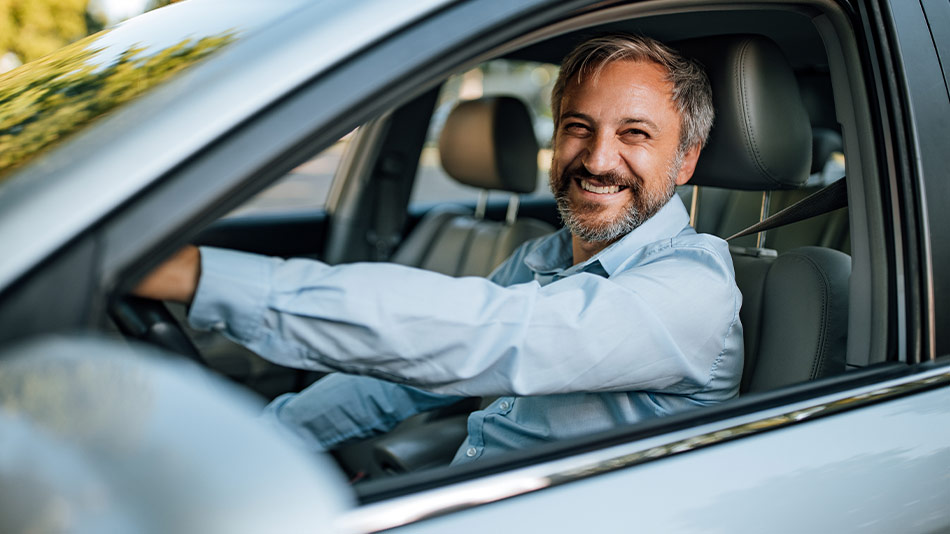 Senior man joyfully driving following successful lens replacement surgery