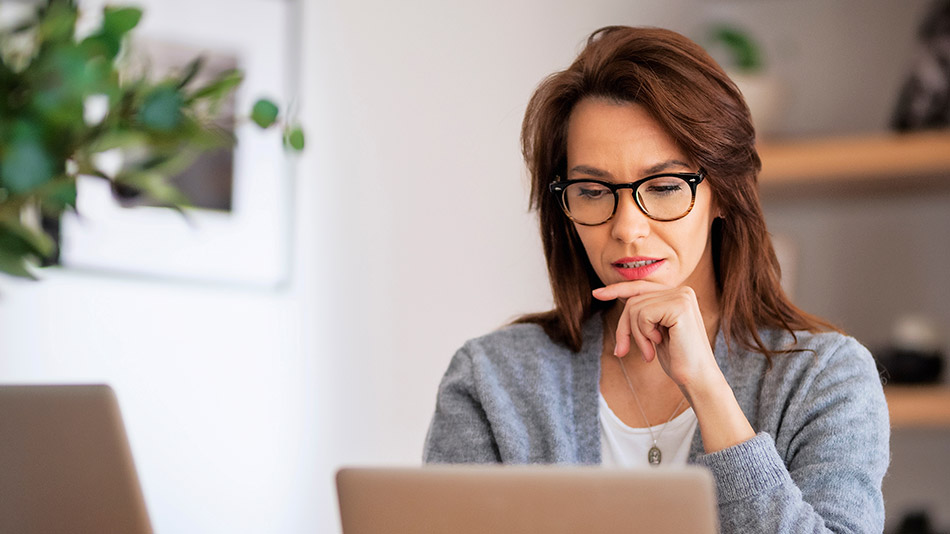 Middle-aged woman focusing on her laptop, deep in thought