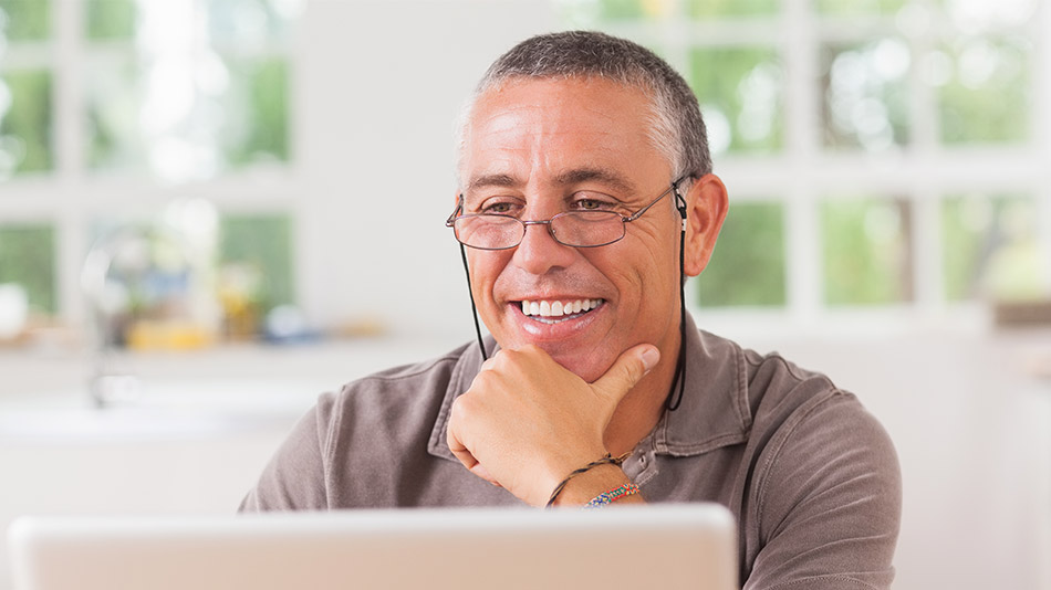 Middle-aged man with glasses, smiling after discovering that blurry vision following lens replacement surgery is temporary and not experienced by everyone