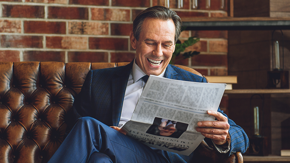 Senior businessman joyfully reading a newspaper without the need for glasses after eye surgery