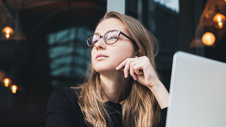 A woman with glasses looking away from her computer screen, thinking if LASIK can prevent glaucoma.