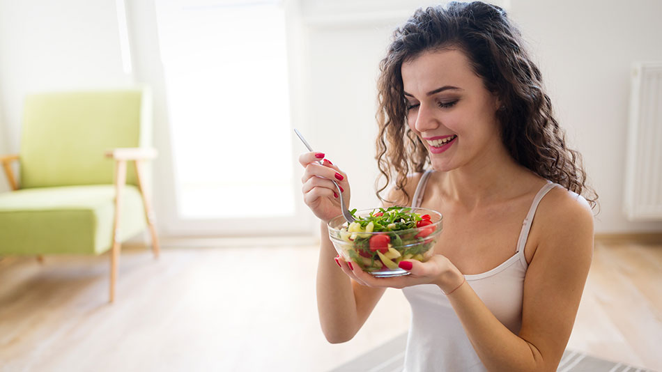 A healthy woman holding a bowl of salad.
