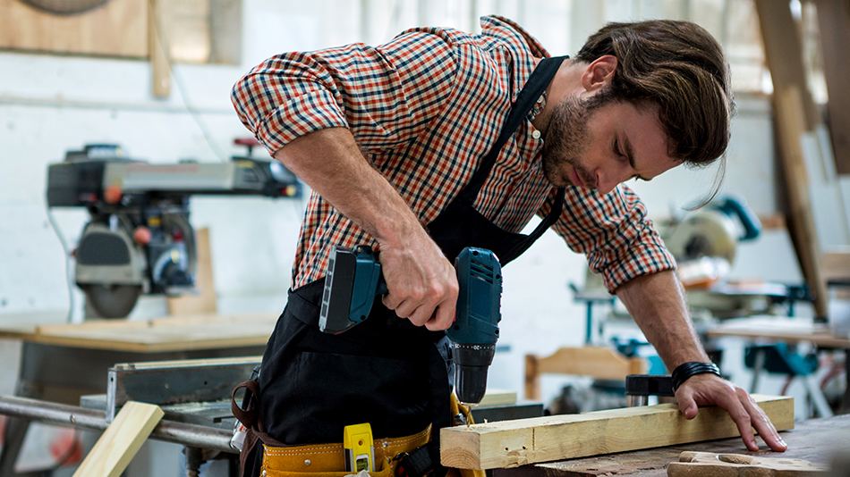 A worker working with wood in a dusty environment.