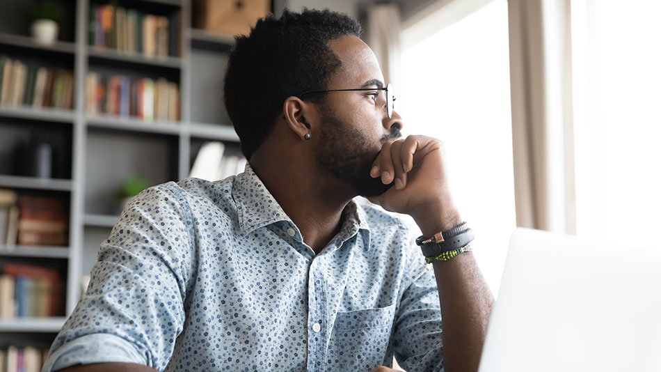 A young man with glasses looks outside through the window.