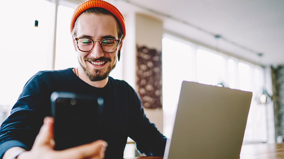 "A man with glasses uses his phone."