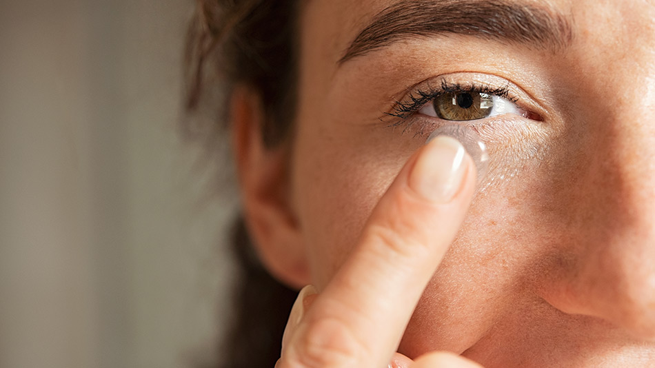 A close-up of a woman inserting her contact lens.